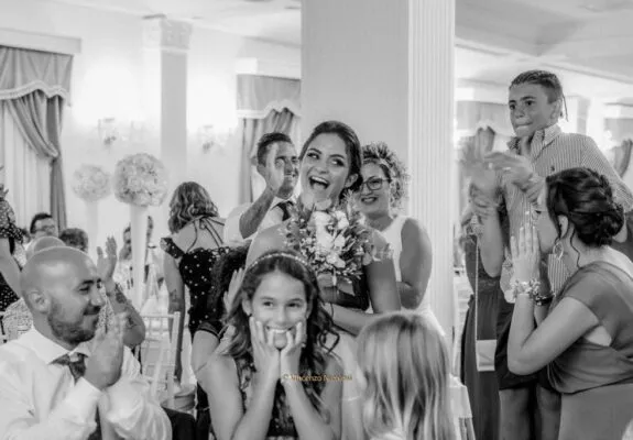 La felicità della ragazza che riceve il bouquet durante il ricevimento, circondata dagli applausi e dai sorrisi degli invitati.